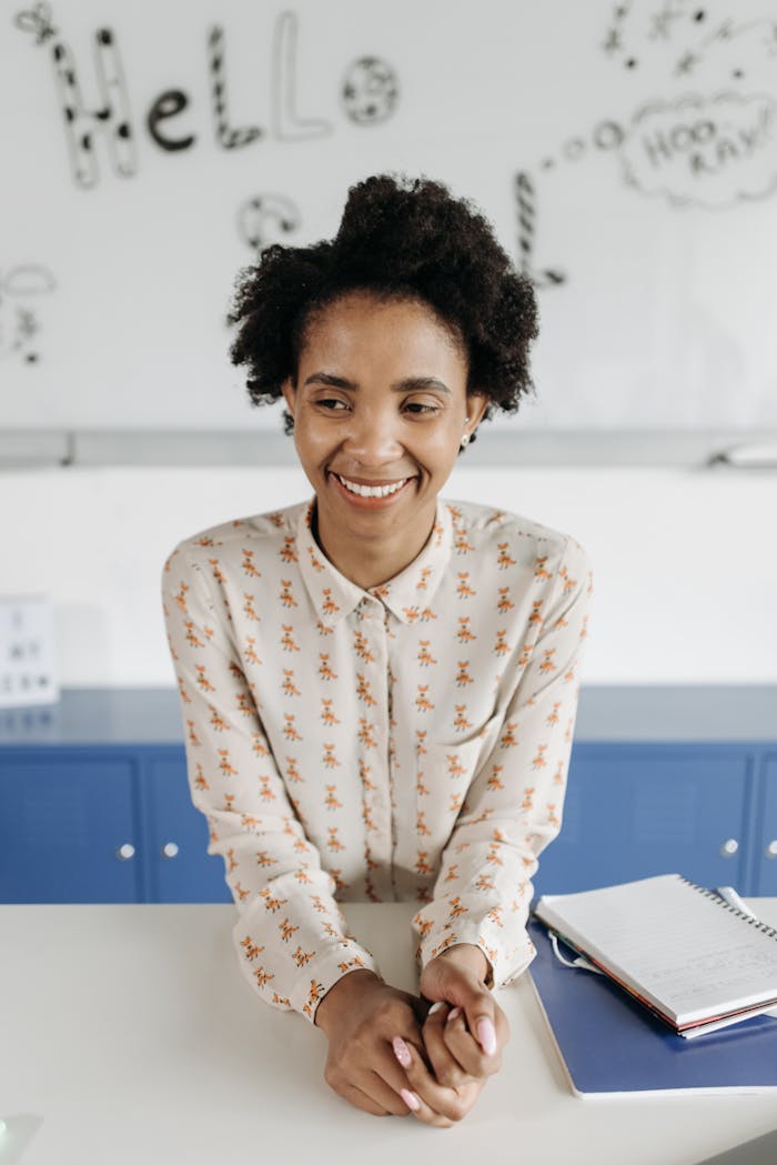 gallery-03 Happy teacher with afro hair smiling indoors. Education and learning concept.