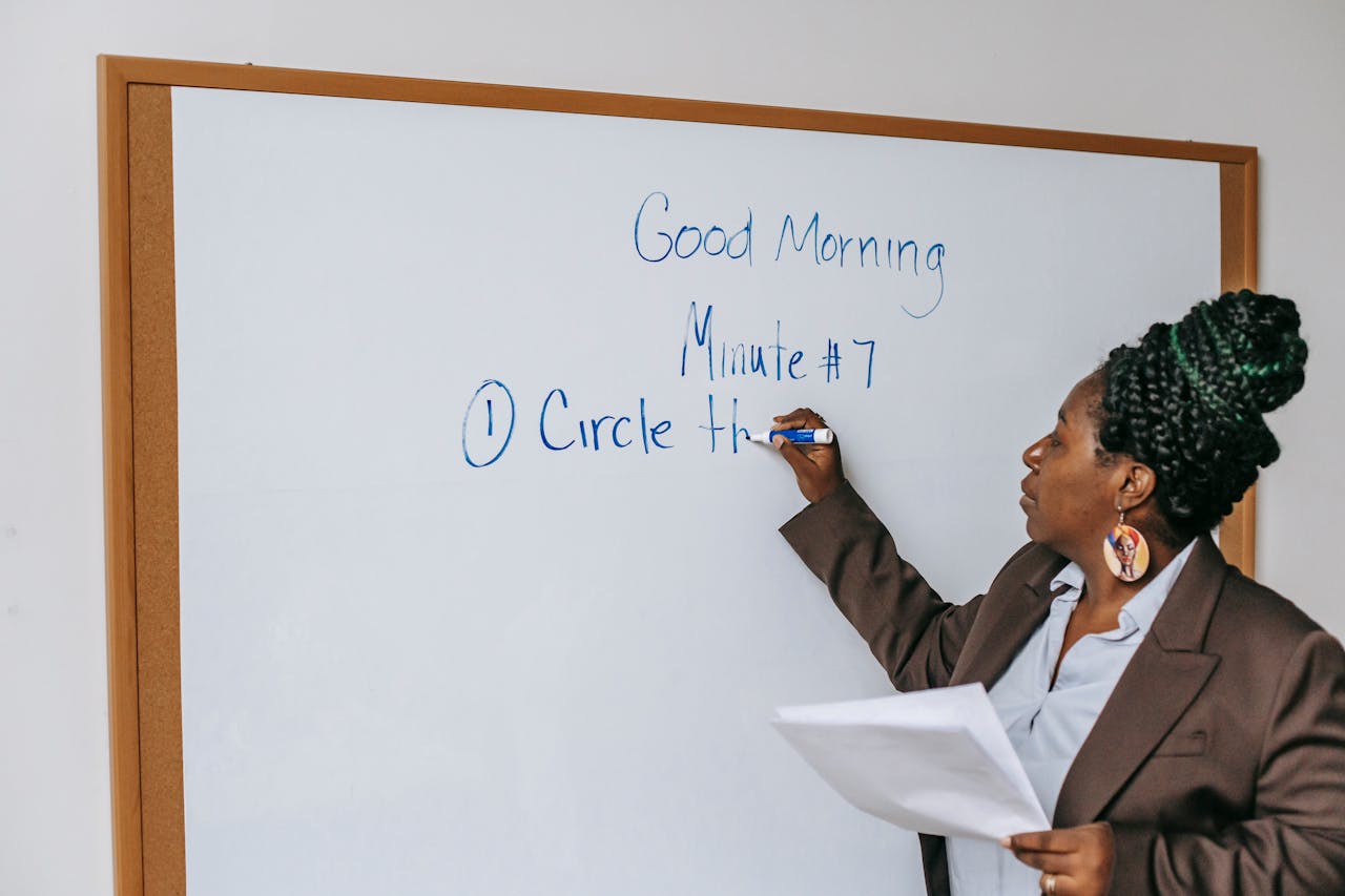 cta-img-01 A professional woman in a classroom writing on a whiteboard during a lecture session.