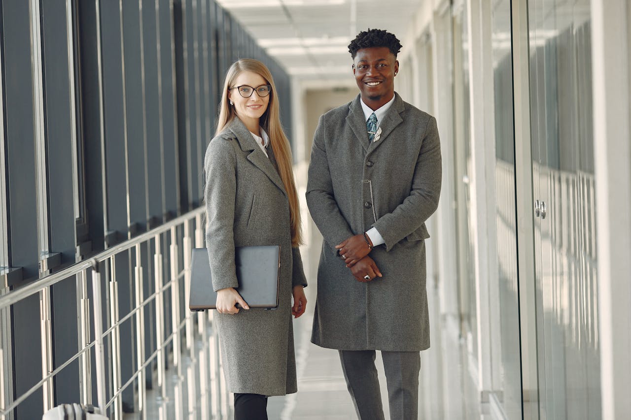 gallery-06 Business professionals standing in a modern office hallway, exuding confidence and style.