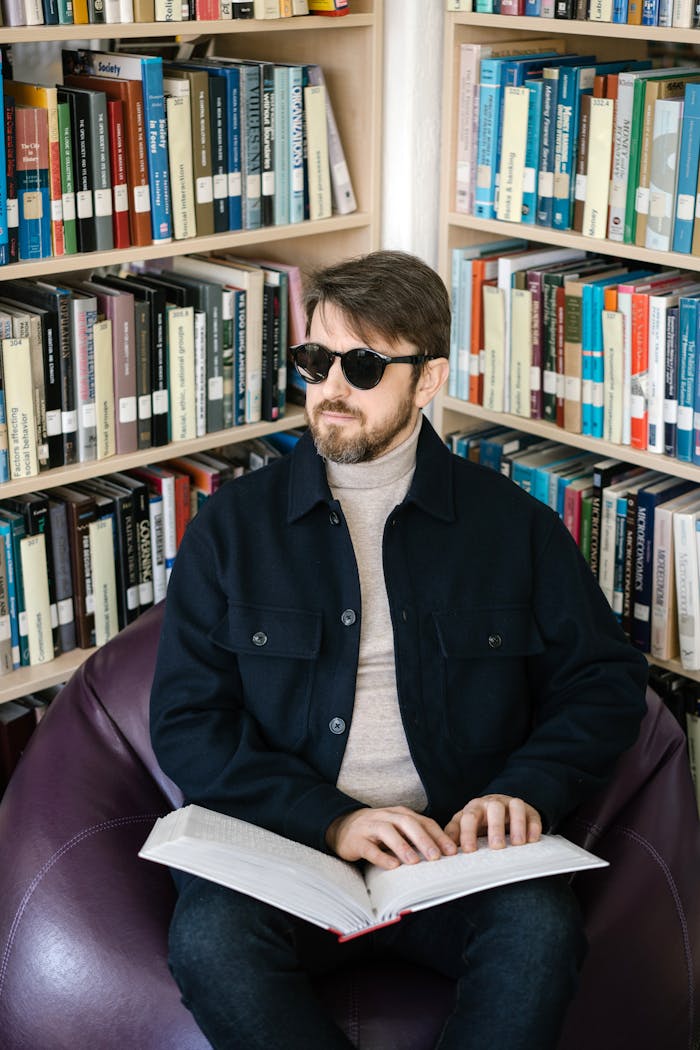 gallery-04 Blind man reading a braille book in a library, promoting inclusivity and accessibility.