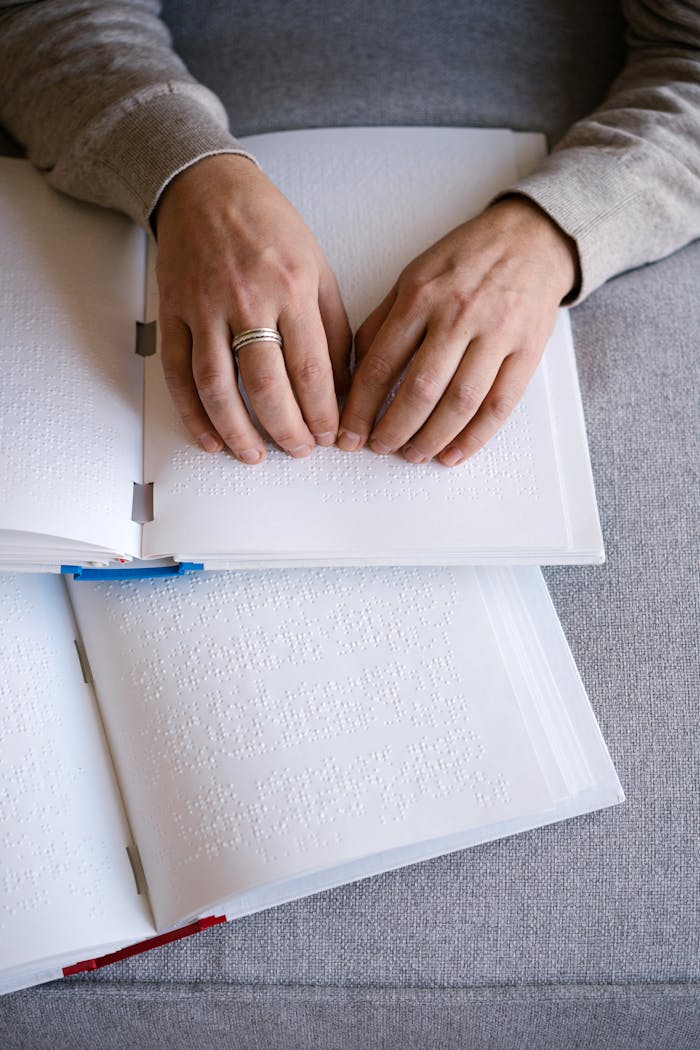 classes-03 Hands reading Braille text on an open book, representing tactile reading and accessibility.